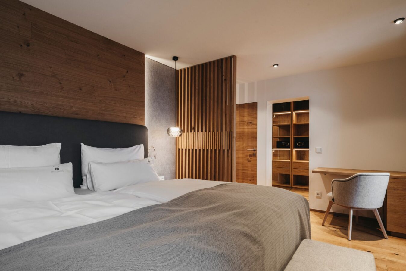 Familiensuite mit Doppelbett, Nachttisch mit Lampe, Spiegel und Schreibtisch mit Sessel