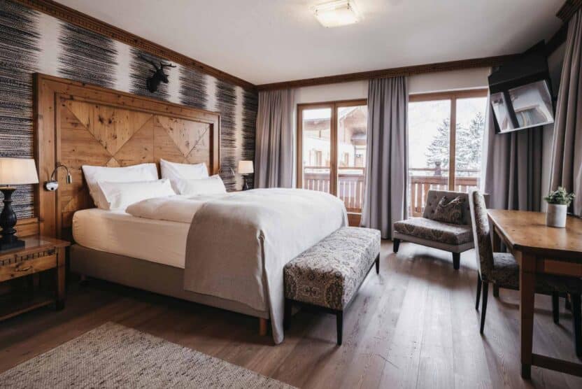 Doppelzimmer Rupi für 2 Personen, Schlafbereich ländlich eingerichtet, Doppelbett mit Nachttisch, Schreibtisch mit Sessel, Fernseher und Balkon
