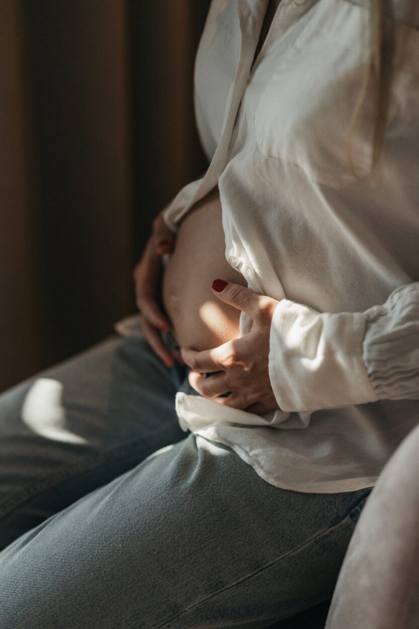 Schwangere mit Babybauch in lockerer Jeans und schöner weißen Bluse